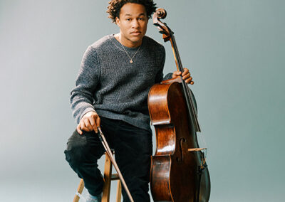 Sheku Kanneh-Mason on a stool holding the cello